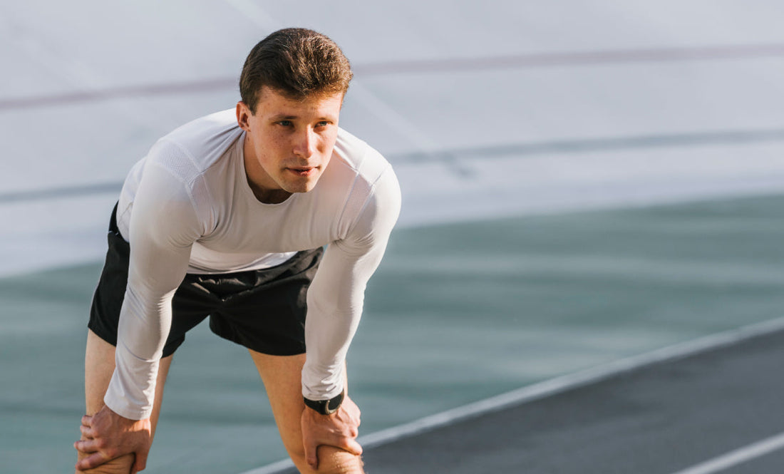 Athlete resting on track after workout, wearing performance gear for recovery and endurance training