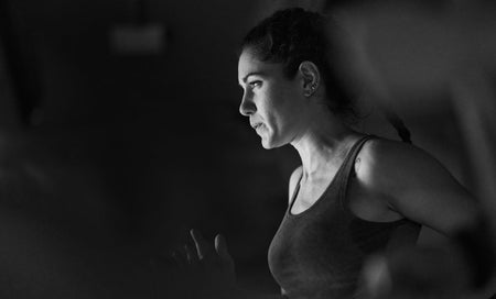 Woman in athletic tank top focused on workout, embodying daily wellness and fitness motivation