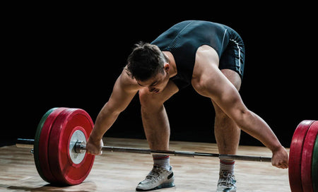 Athlete lifting barbell with red weight plates, focused on strength training and fitness performance.