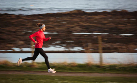 Woman jogging outdoors in red athletic wear for daily wellness and active lifestyle