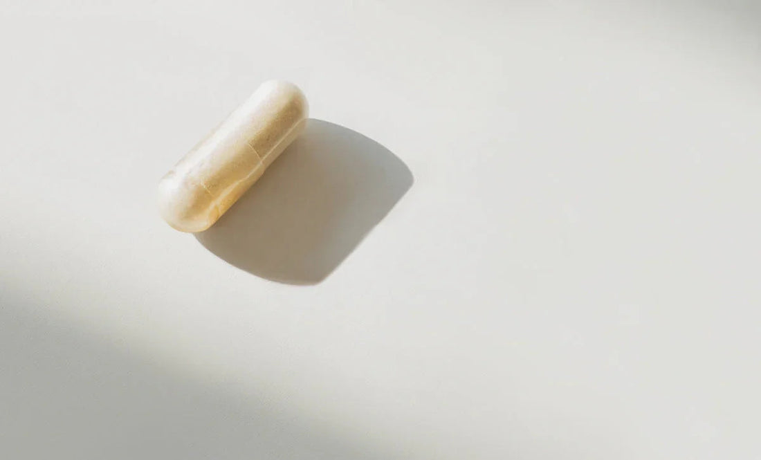 Beige supplement capsule on white surface with soft shadow, science-backed daily wellness