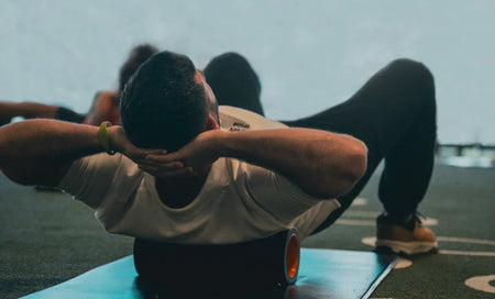 Man doing core exercise with foam roller on mat, fitness recovery gear