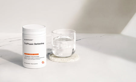 TriPhasic Berberine supplement bottle beside glass of water on marble surface, science-backed wellness formula