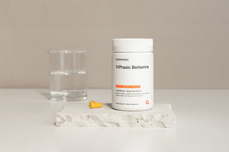 TriPhasic Berberine supplement bottle with yellow capsules and water glass on stone slab, for metabolic and GI support