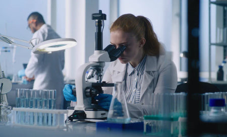 Scientist examining samples under microscope in modern lab for research-backed wellness