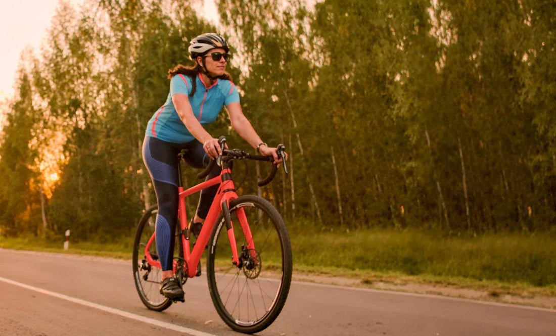 Woman cycling on road at sunset, wearing helmet and athletic gear, promoting active wellness lifestyle